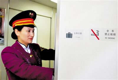 2011年1月8日,列车工作人员在贴有禁烟标志的动车上整理行李。